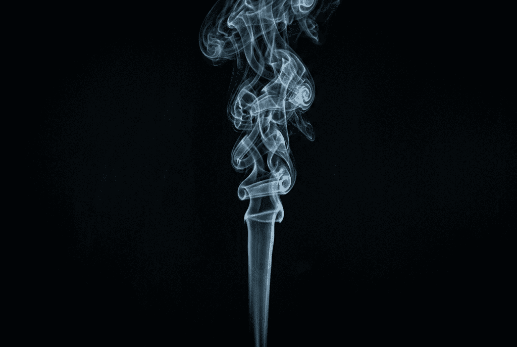 A minimalist fine art photograph of a single, perfectly vertical column of rising, swirling, wispy blue and grey smoke, set against a complete black void with sharp rim lighting on the smoke plumes.